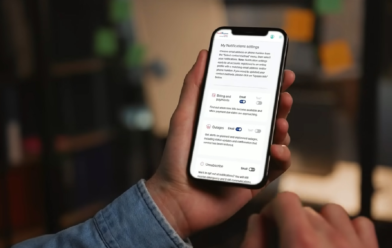 A hand holds a phone while someone signs up for NWE alerts